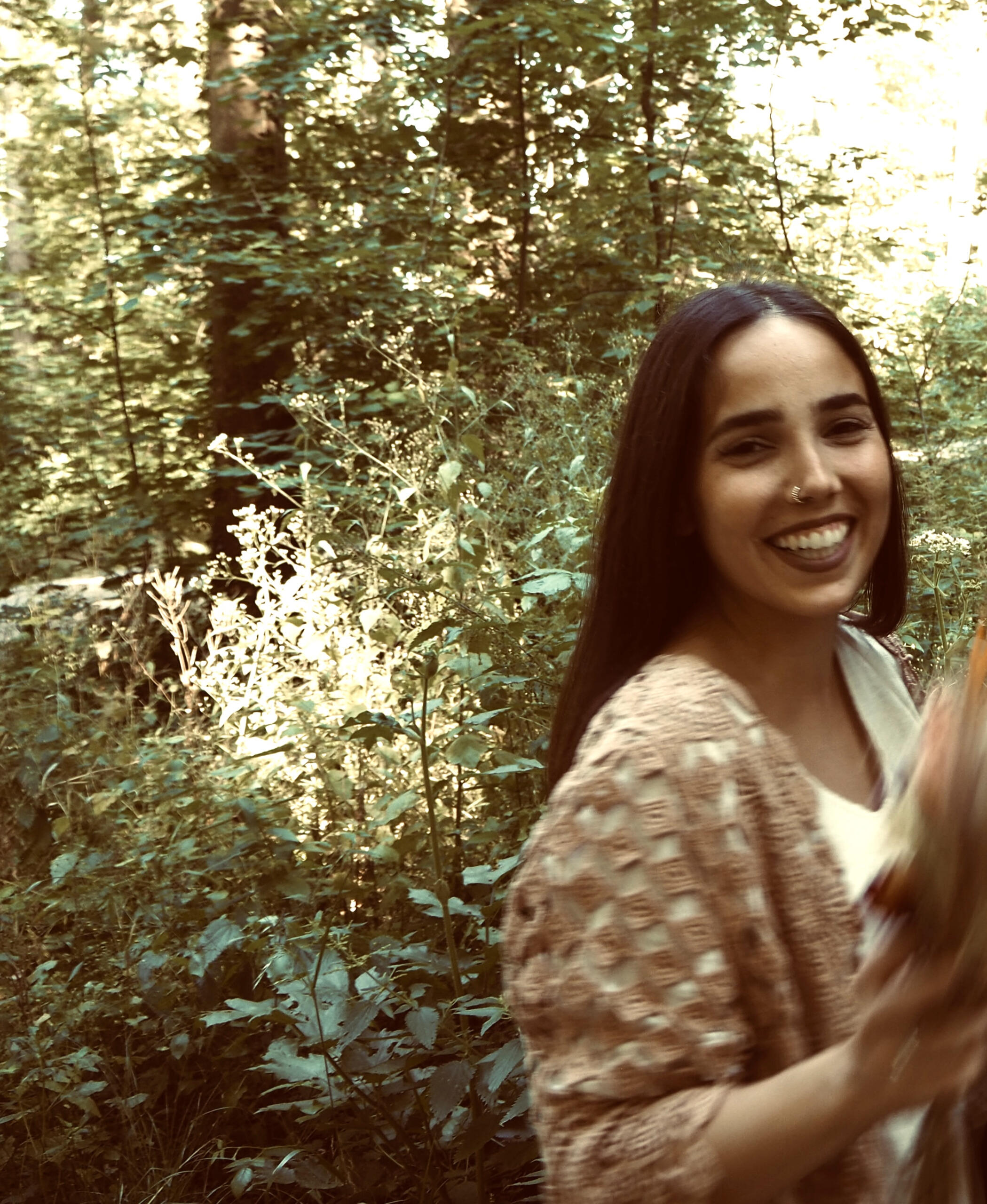 Ein Foto von Meli in einem Wald. Sie lacht und schaut in die Kamera.
