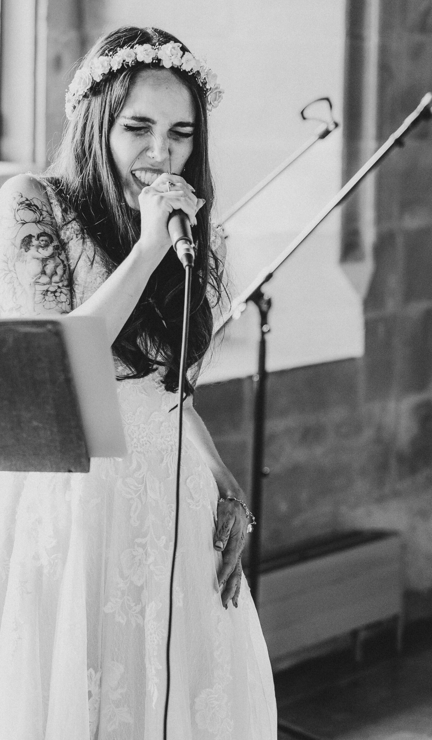 Ein Foto von Meli im Brautkleid singend am Mikrofon. Sie hat die Augen geschlossen.